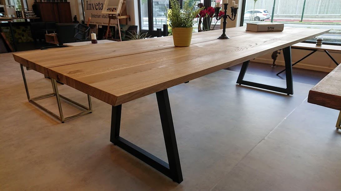 Langt håndlaget bord med kraftig bordplate og mørkt understell